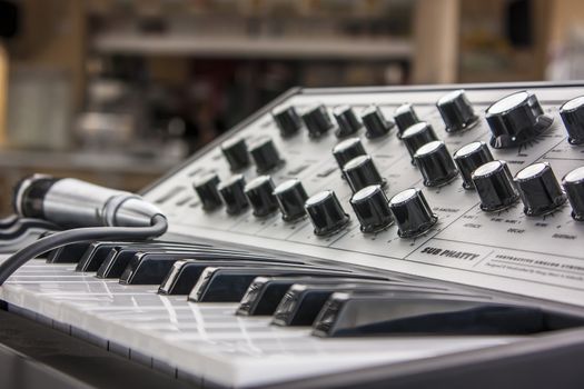 Small vintage musical keyboard with potentiometers to adjust the sound and a microphone to sing.