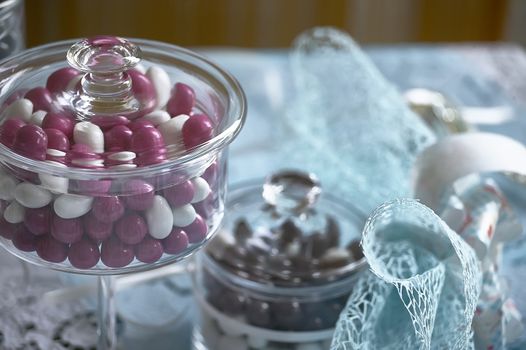 Still life with colored candies in glass containers and blue ribbons to celebrate baptism.