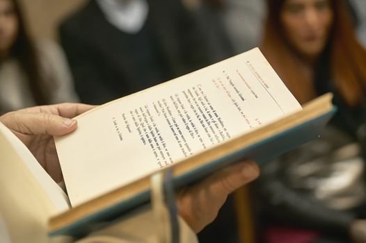 Book of the Gospel held by the priest during a Catholic celebration in church full of faithful.
