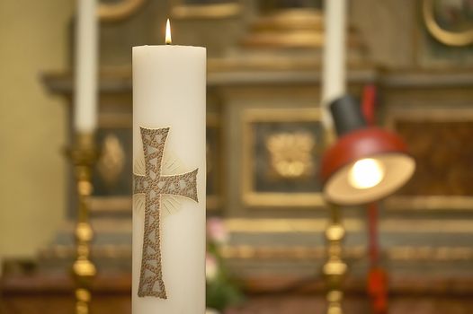 Horizontal shot of an Easter candle with the cross lit in the church during the ceremony of a baptism.
