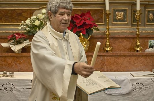 Parish priest who hands the candle to his parents during the Catholic rite of baptism.