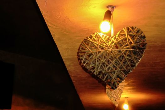 Interior decoration in the shape of a heart attached to the ceiling of a room, lit by a lit lamp.