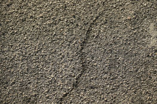 Texture of the worn and ruined asphalt with a crack in the middle.