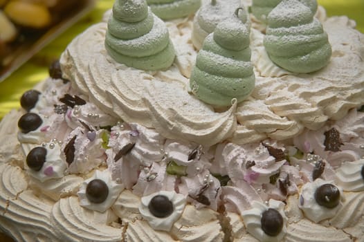 Detail of a meringue trout sprinkled with icing sugar on top and chocolate decorations underneath.