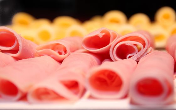 detail of ham in rolls with cheese out of focus in the background