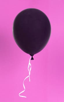 Black balloon isolated on a pink background