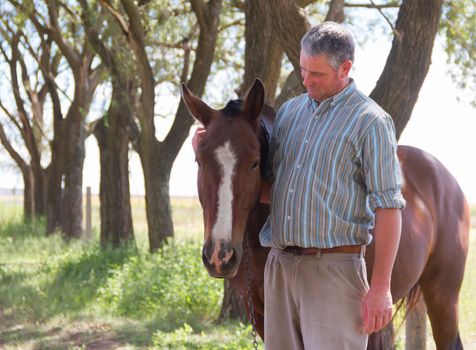 Smiling man with his horse in the Argentine countryside