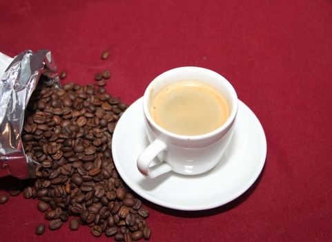 white cup of coffee with beans on background board