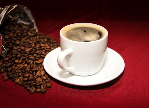 white cup of coffee with beans on background board