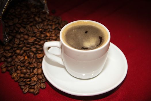 white cup of coffee with beans on background board