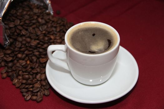 white cup of coffee with beans on background board