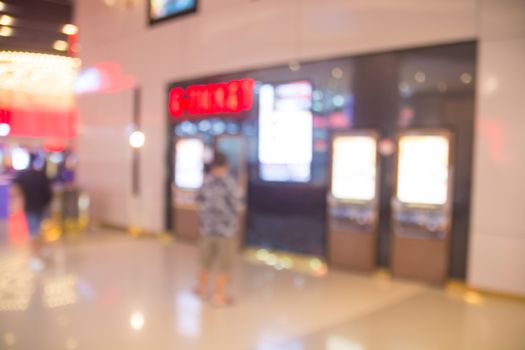 Abstract blur people buying movie ticket from e-ticket selling machine in front of the theater