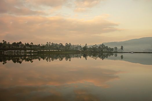 Reflection of clouds in the sky, the hills, the farm estate on the lake Cileunca