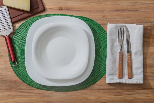 white plate on a wooden table with rustic cutlery and green tablecloth