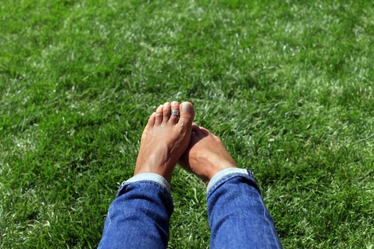 Bare feet in green grass, woman relaxing in nature