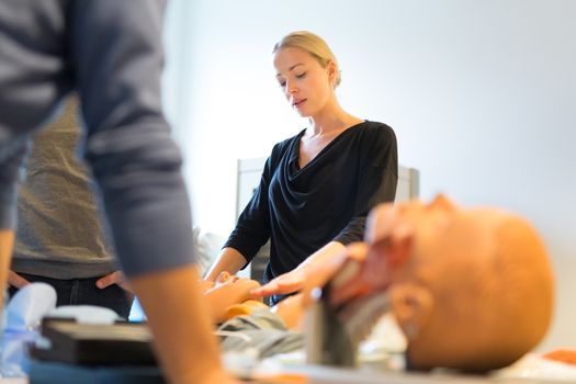 Medical doctor expert instructor displaying method of patient intubation on medical education training and workshop. Participants working in teams learning new medical procedures and techniques.