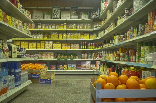 Interior of a supermarket with view of shelves full of goods and groceries on display.