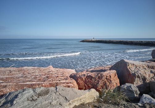 Wide angle view of the sea, the beach and the cliff overlooking the sea itself, with a man in the distance looking at the sea and enjoying the peace and tranquility that only this magical place can give.