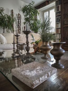 Still life with candlesticks and vintage vases inside a living room with antique furniture.