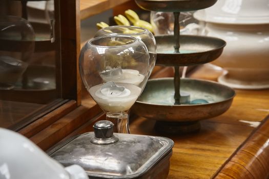 Still life with various vintage objects resting on top of a historic piece of furniture: Glasses, metal boxes and objects for decorative use.