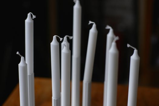 Image containing many still unused wax candles to be used.