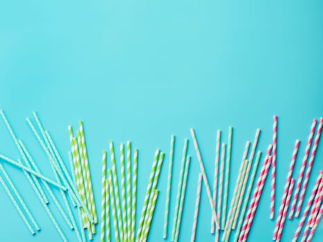 Colorful paper straws on blue background. Ecology product. Equipment for single use. Plastic alternative. Zero waste concept. Copy space for text or design. Top view or flat lay