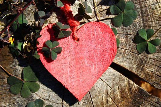 The picture sows a red heart on wooden ground