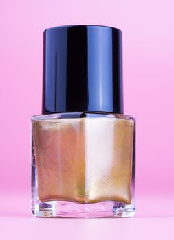 Nice bottle of gold nail polish, pink background