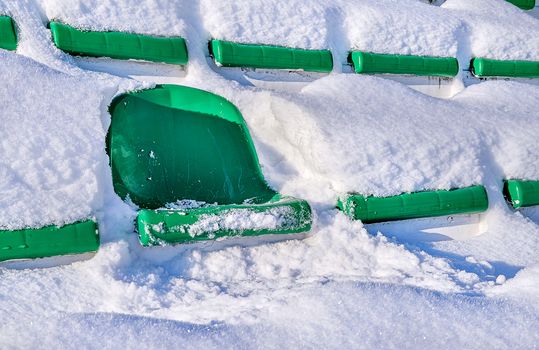 Green seats of a sports stadium, covered with snow. The concept of closing the summer season of games