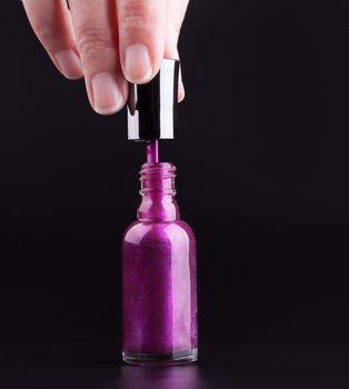 Female hand opening a bottle of purple nail polish
