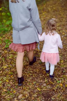 Beautiful little girl on a walk in the park on a sunny day. Autumn day