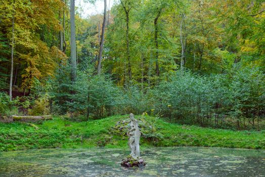 cement statue of a woman in the woods.
