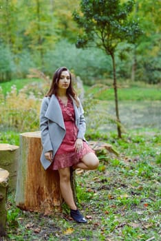 Woman standing next to a tree in park in golden autumn.