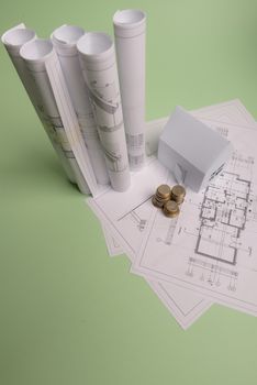 White family paper house , stack of money coins, house projects plan and blueprints on mint background paper. Minimalistic and simple concept, style. Horizontal orientation