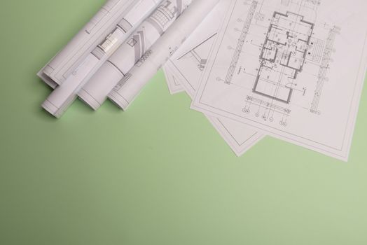 White family paper house , stack of money coins, house projects plan and blueprints on mint background paper. Minimalistic and simple concept, style. Horizontal orientation