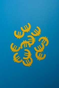 Paper yellow symbols of euro currency on blue background. View from above with copy space