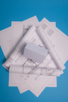 White family paper house over block of flats on blue background paper. Minimalistic and simple concept, style. Copy space. Vertical orientation.