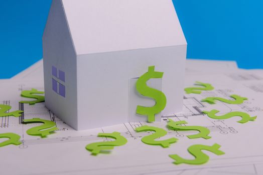 Paper skyscrapers , us dollar money, house projects plan and blueprints on blue background paper. Minimalistic and simple concept, style. Horizontal orientation. View from above. Copy space.