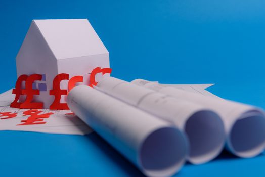 White family paper house , british pound money symbol , house projects plan and blueprints on mint background paper. Minimalistic and simple concept, style. Vertical orientation. View from above. copy space