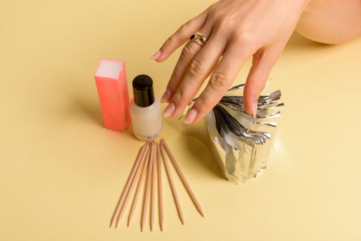 The procedure for removing varnish from nails hybrid nails in progress. Gel nail polish remover foils on woman's hands