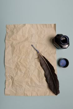 Raven feather, inkwell and old yellowed paper on red background. Copy space. Old letter.
