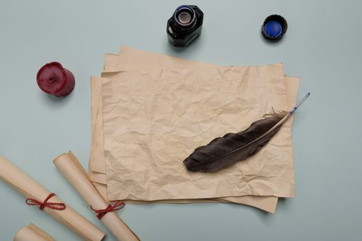 Raven feather, inkwell and old yellowed paper on red background. Copy space. Old letter.