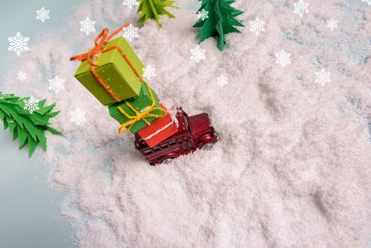 a toy car carries presents under the Christmas tree at snow. view from above. copy space