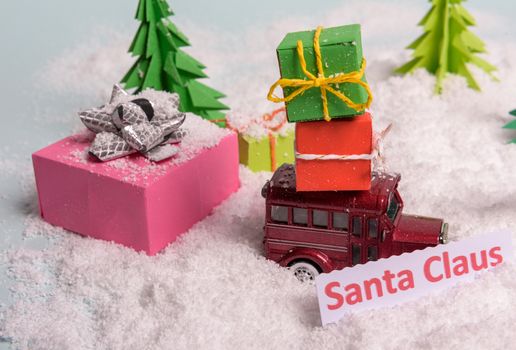 a toy car carries presents under the Christmas tree at snow. view from above. copy space