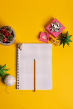 gift box and green origami trees with notepad on yellow desk, table