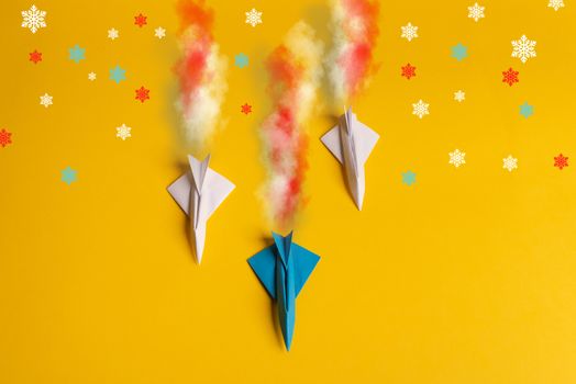 Group of paper plane in one direction and with one individual pointing in the different way on yellow background. Smoke coming out from aircraft tails