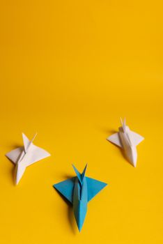 Group of paper plane in one direction and with one individual pointing in the different way on yellow background. Smoke coming out from aircraft tails