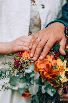 Crop blurred just married couple in elegant clothes hugging and holding beautiful bouquet of fresh colorful flowers in composition with green and brown herbs