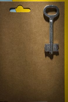 Metal old key on a brown cardboard tablet