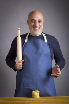 A man with a rolling pin on a background of gray wall